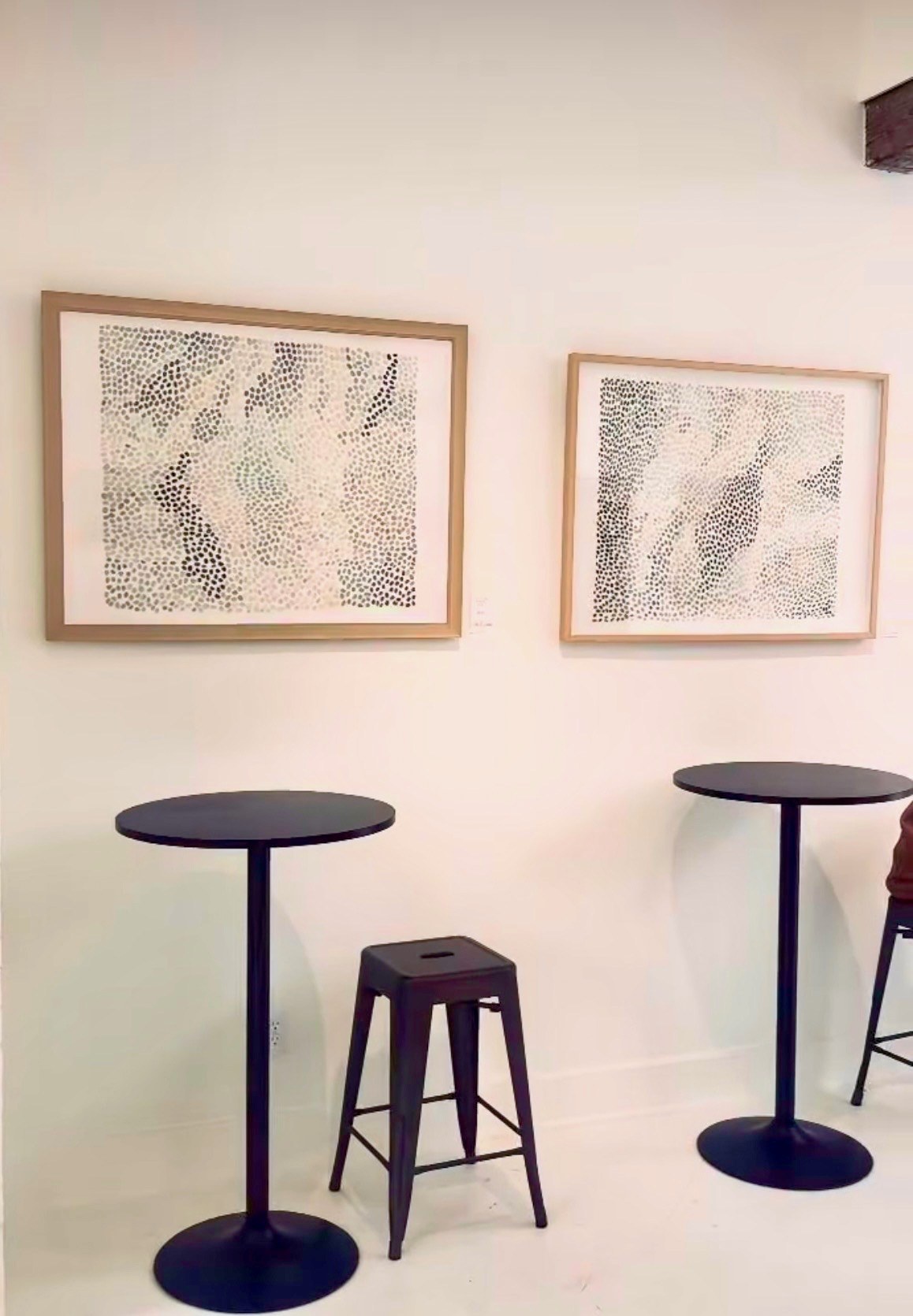 Two framed Leva Art works displayed above stools at ARS Gallery in Lakeside, Michigan